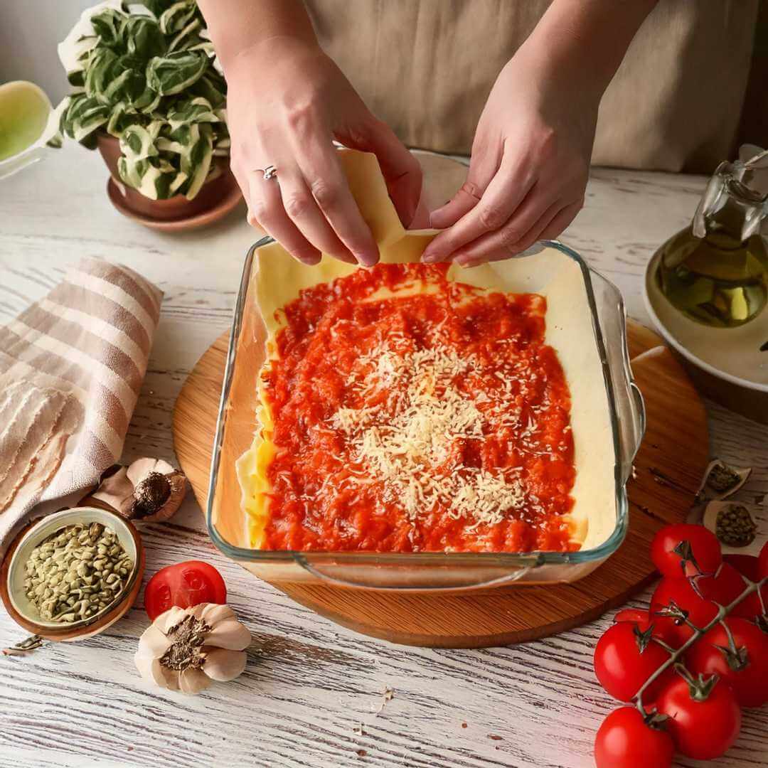 Preparazione della Lasagna proteica alla bolognese Pronte con salsa e formaggio, ideale per dieta chetogenica e alimenti proteici.