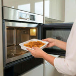 Persona che prende una porzione di pasta dal forno a microonde, ideale per la Box G8 Premium Spesa mensile.