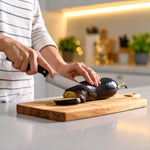 Un cuoco taglia una melanzana su un tagliere di legno, pronto per preparare una ricetta sana e gustosa.