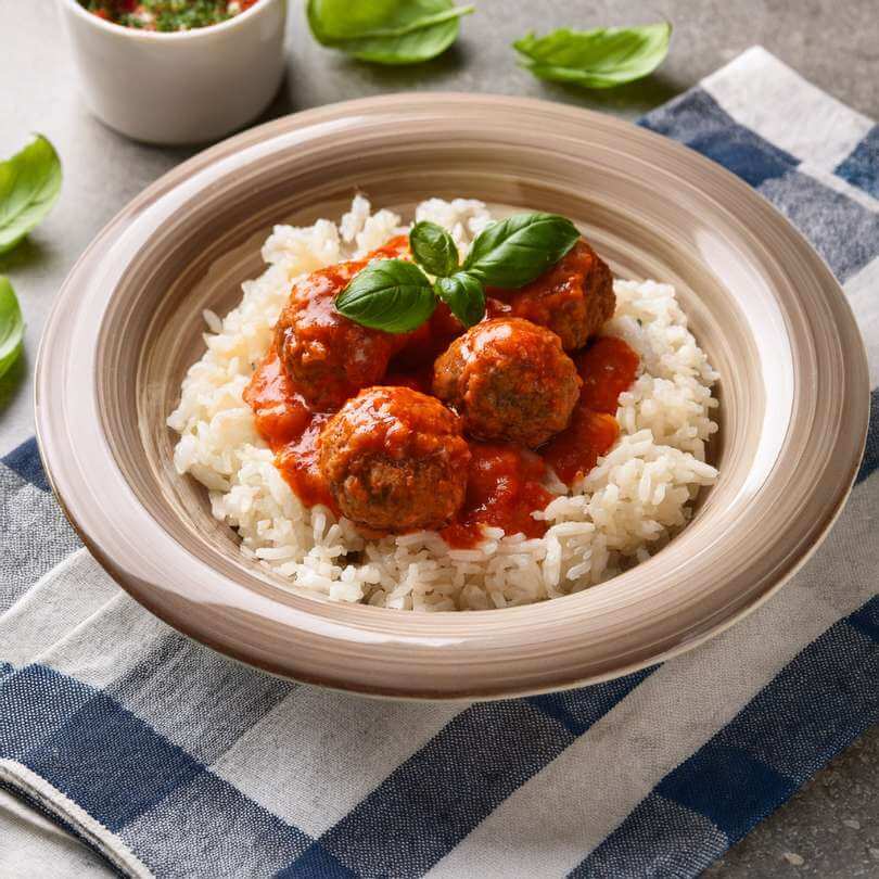 Pollo e carne macinata in salsa di pomodoro serviti su riso bianco, piatto gustoso e semplice da preparare.
