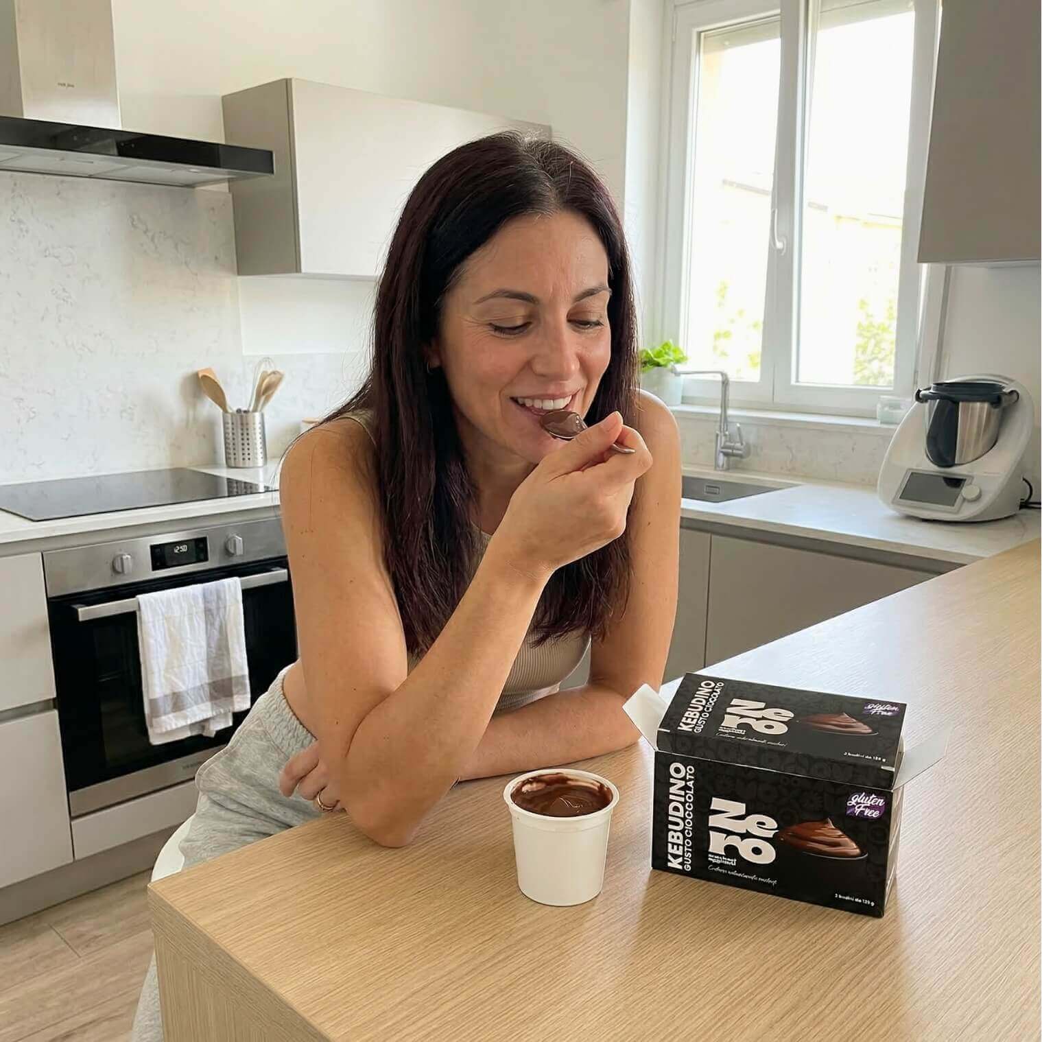 Kebudino proteico al cioccolato: donna gusta un delizioso budino al cioccolato in cucina, dieta chetogenica.