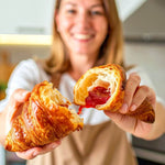 15 Cornetti proteici ripieni di purea alla fragola, mostrati da una donna sorridente.