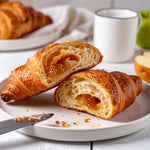 15 Cornetti proteici ripieni di purea alla mela su un piatto bianco con tazza e mela sullo sfondo.