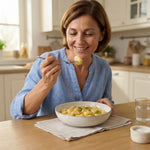 Donna felice mentre mangia Gnocchi Keto crema allo zafferano keChef in una cucina moderna.